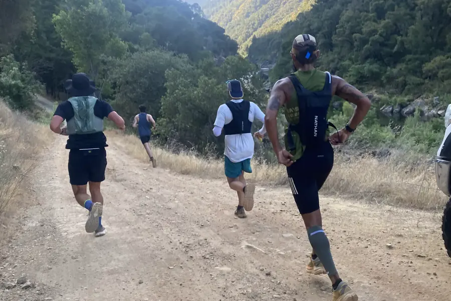 Trail runners descending a dry dirt path into an Auburn canyon