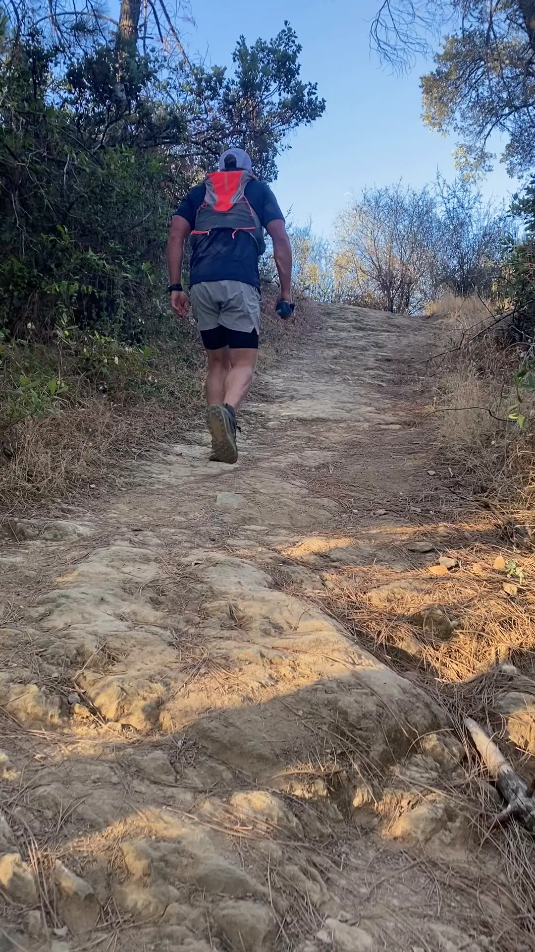 Runner hiking a steep, rocky Auburn trail with a hydration vest