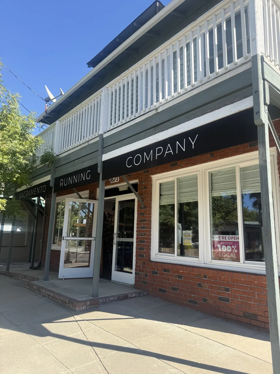 Sacramento Running Company storefront with black awnings, brick walls and an open entrance.